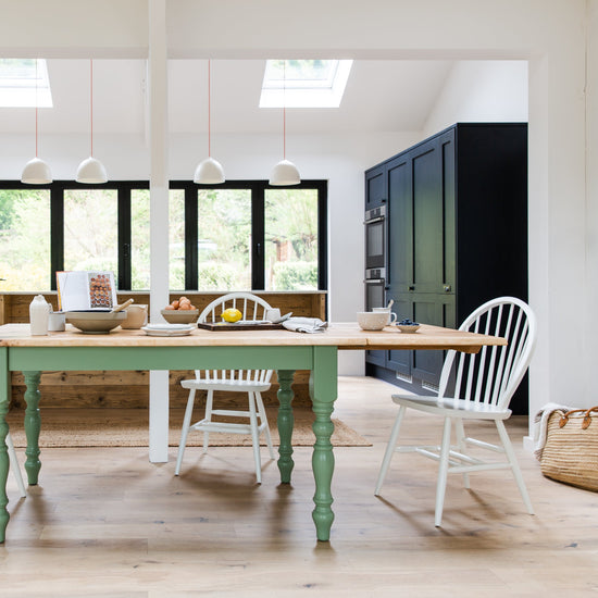 A kitchen with a green table and chairs.