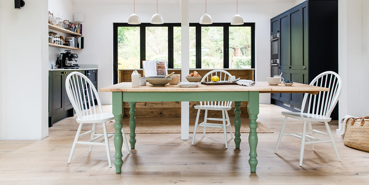 Green Farmhouse Table in a modern Kitchen with Chairs at either end. 