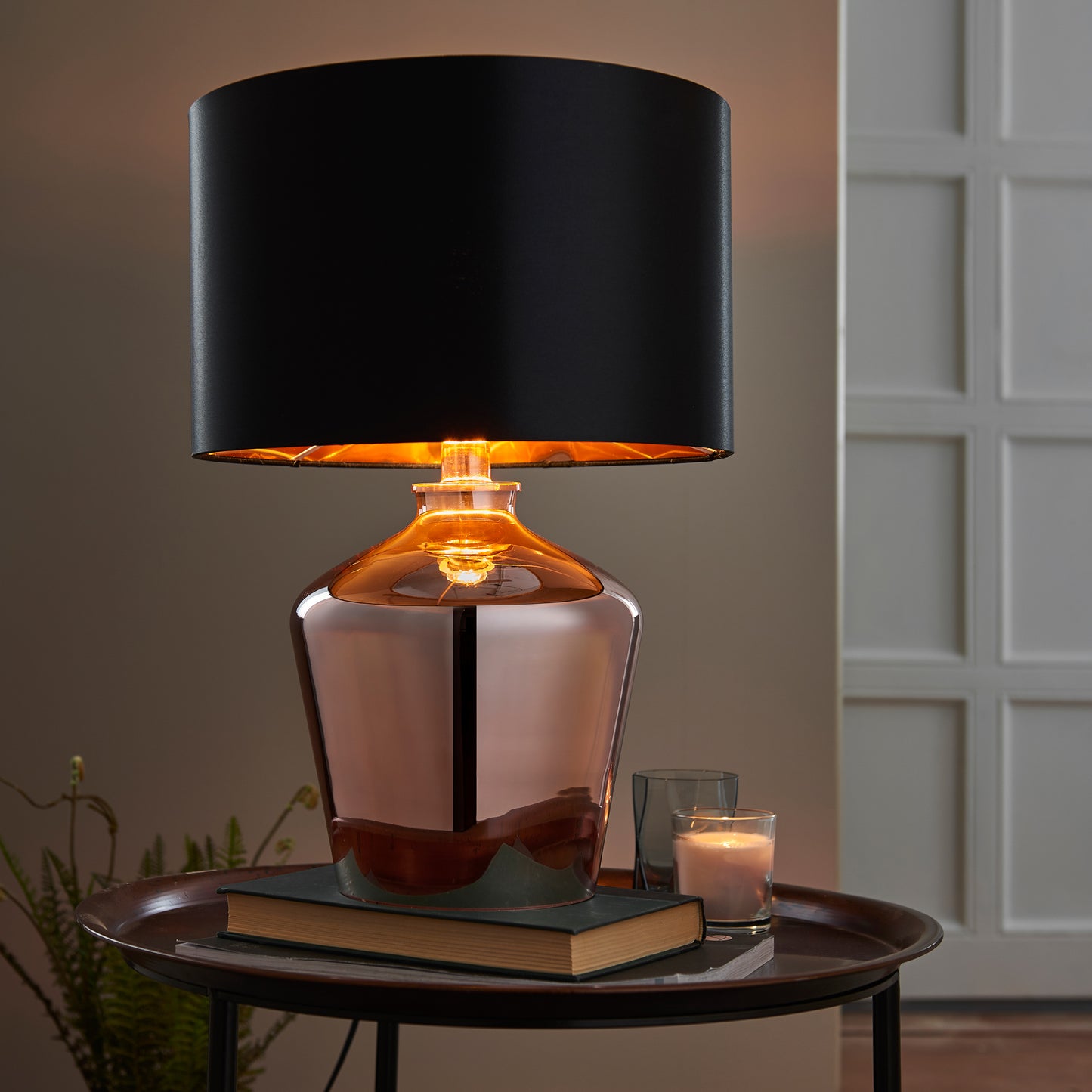 A copper table lamp with a black shade and a book, perfect for home interior decor.
