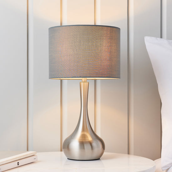 An elegant Piccadilly Table Lamp in nickel and dark grey, with a grey shade, to enhance interior decor on any white table.