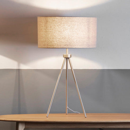 An Interior decor Tri Table Lamp from Kikiathome.co.uk on a wooden table next to a wall.