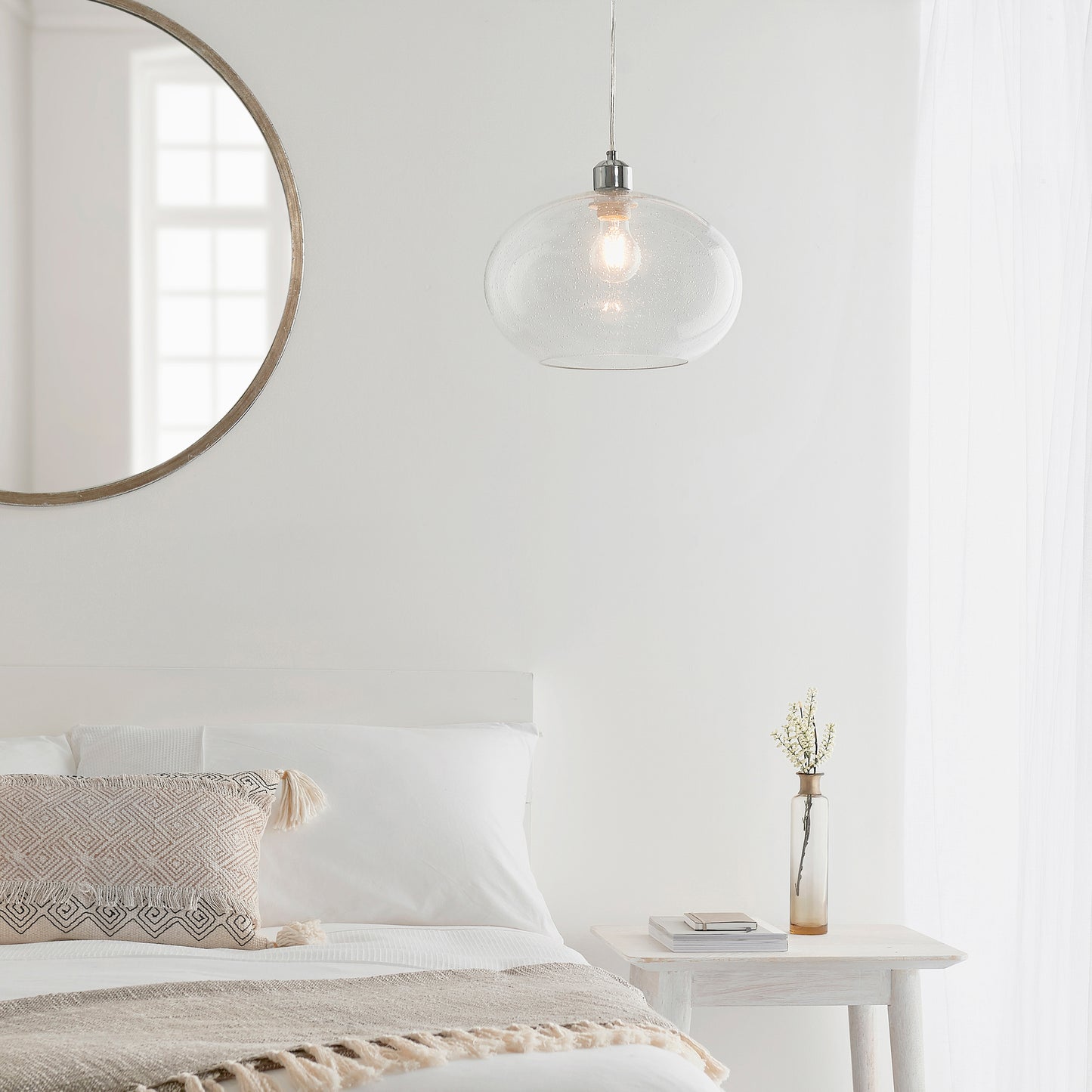 A white bedroom with a round Dimitri Shade Clear Glass mirror as home furniture above the bed.