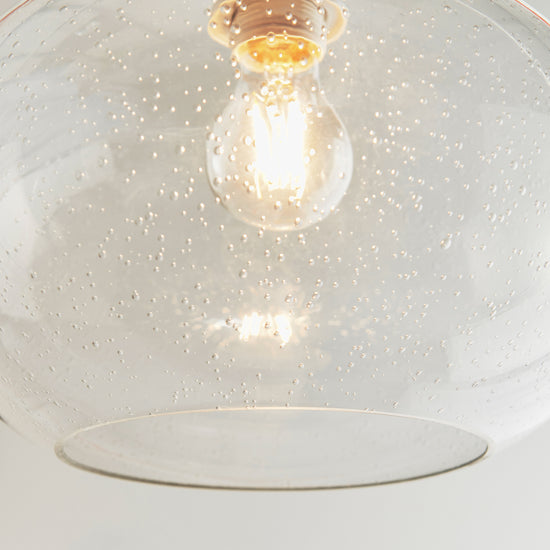 A Clear Glass pendant light with a light bulb hanging from it, sold by Kikiathome.co.uk for interior decor.
