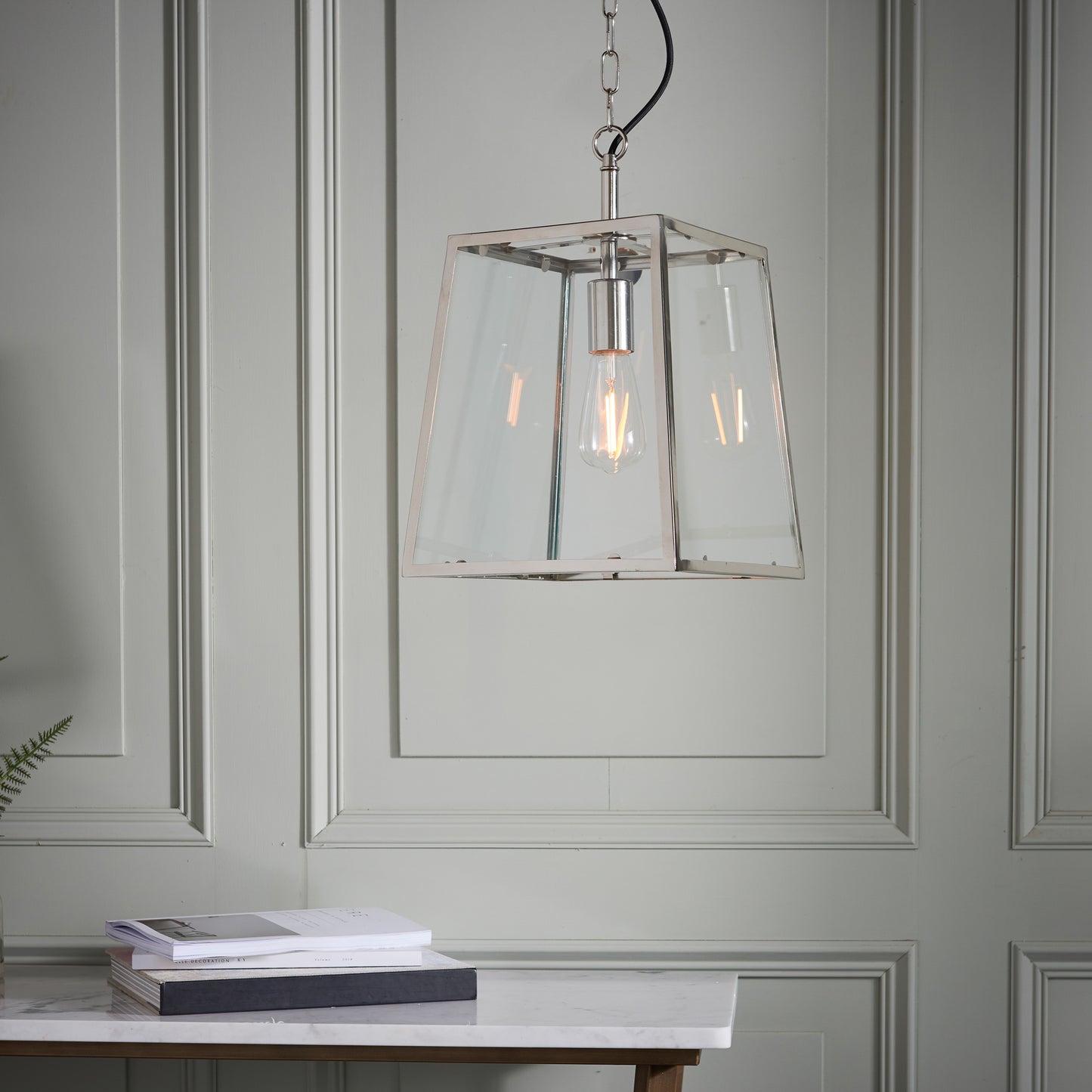 A stylish pendant light nickel hanging over a table, adding elegance to the room's interior decor.