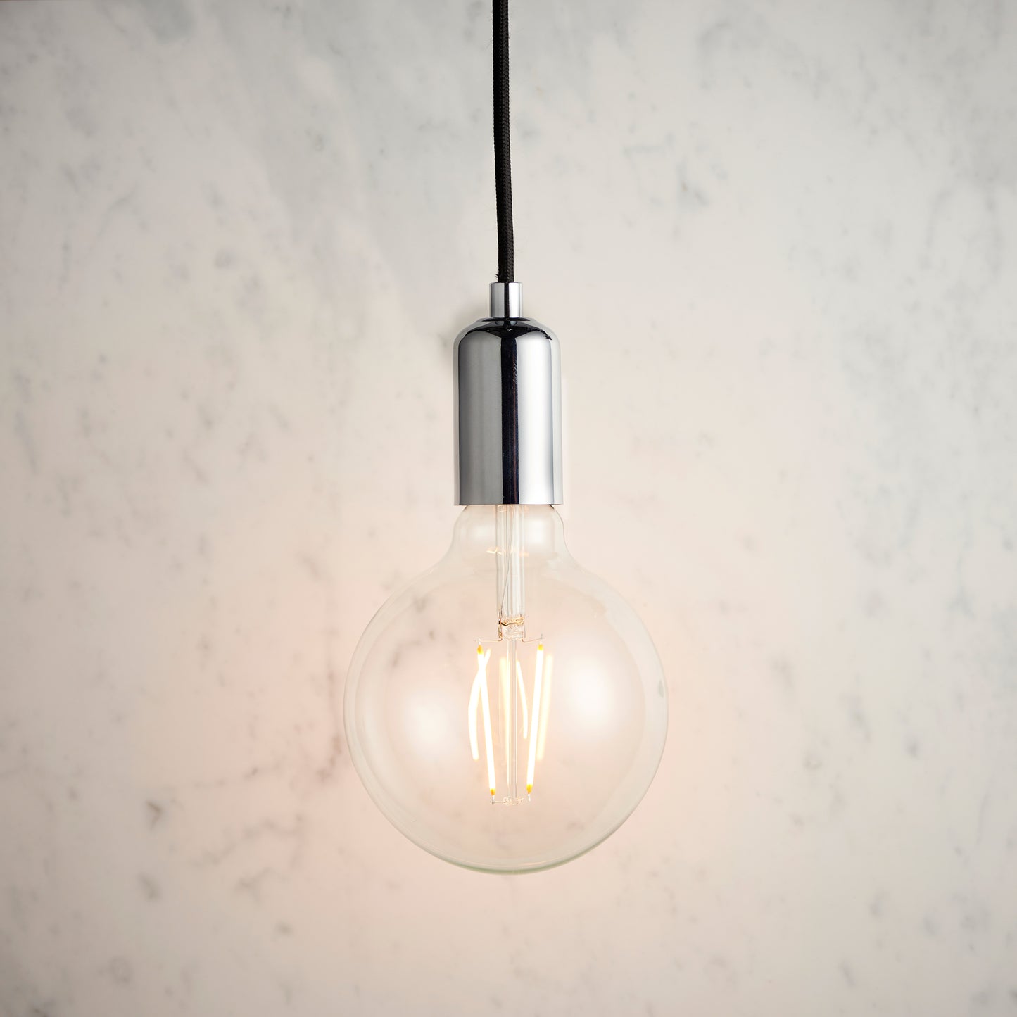 A Studio Pendant Light Chrome hanging on a marble wall, perfect for interior decor and home furniture from Kikiathome.co.uk.