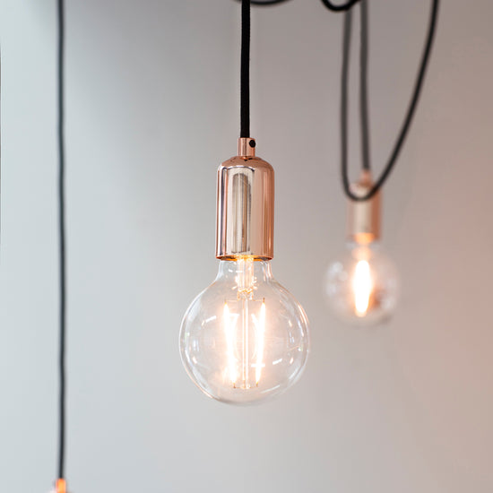Three Studio 6 Cluster Pendant Light Copper light bulbs hanging from a black cord, ideal for home decor.