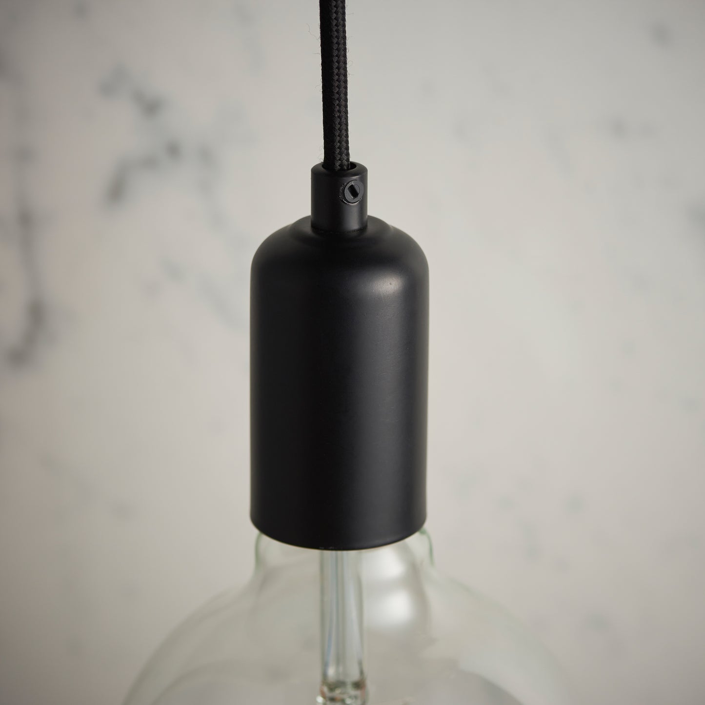 A Studio Pendant Light Matt Black hanging on a marble countertop, perfect for interior decor and home furniture enthusiasts from Kikiathome.co.uk.