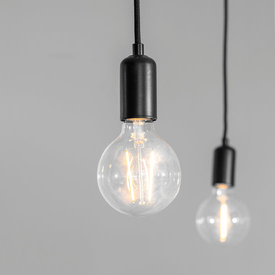Two Studio 6 Cluster Pendant Light bulbs hanging on a gray background, produced by Kikiathome.co.uk for home decor.