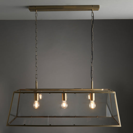 A Hurst 3 Pendant Light Antique Brass with three bulbs hanging from the ceiling, perfect for interior decor and home furniture enthusiasts.