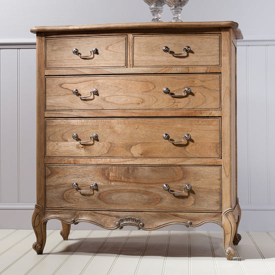 A home furniture 5 drawer chest with a vase on top.