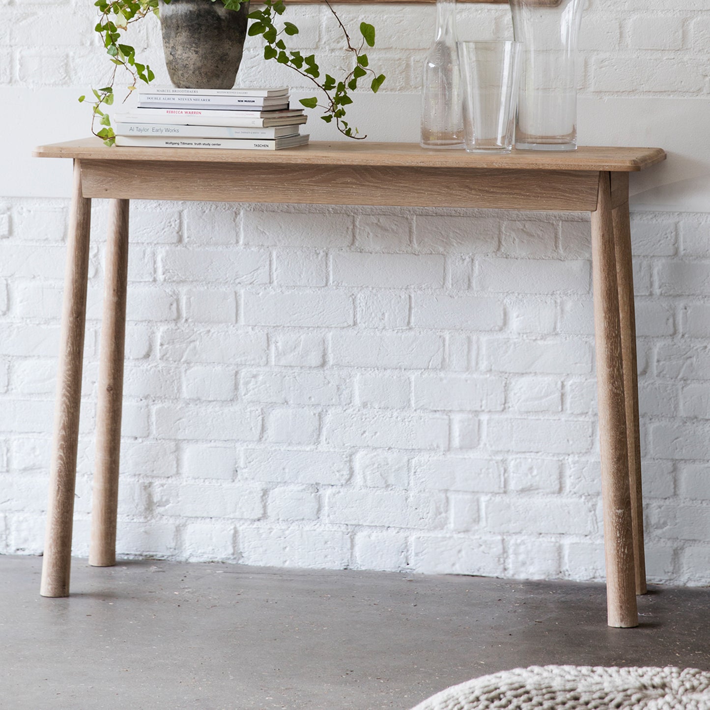 A Tigley Console Table 1100x400x800mm with a plant on it, perfect for home furniture and interior decor from Kikiathome.co.uk.