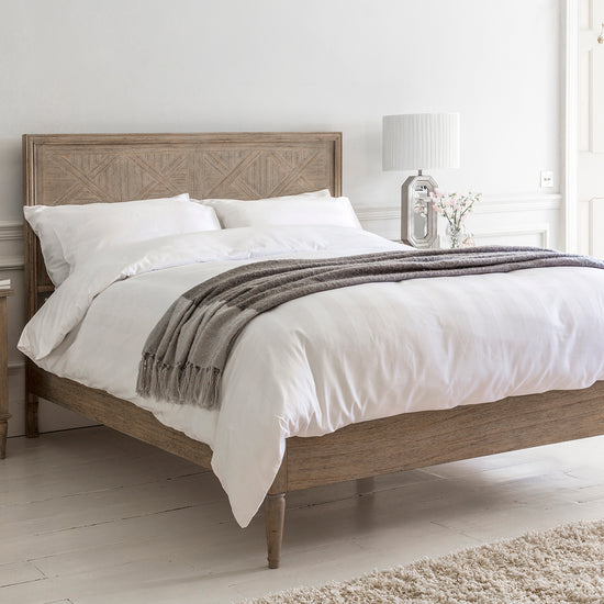 An elegantly decorated bedroom featuring a Kikiathome.co.uk Belsford 5' Bed and a sleek white dresser.