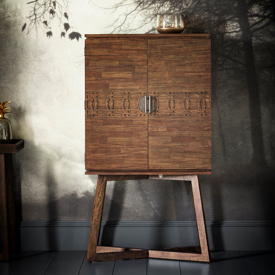 A Dartington Retreat Cocktail Cabinet in front of a wall with a tree in the background, adding elegance to your interior decor.