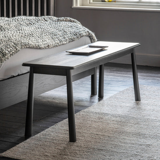 An interior decor featuring a Tigley Dining Bench Black 1300x360x460mm by Kikiathome.co.uk alongside home furniture in a room with a bedside table.
