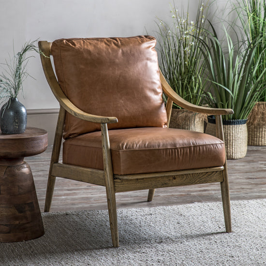 A luxurious Reliant Armchair in brown leather, placed in front of a potted plant, perfect for interior decor at home.