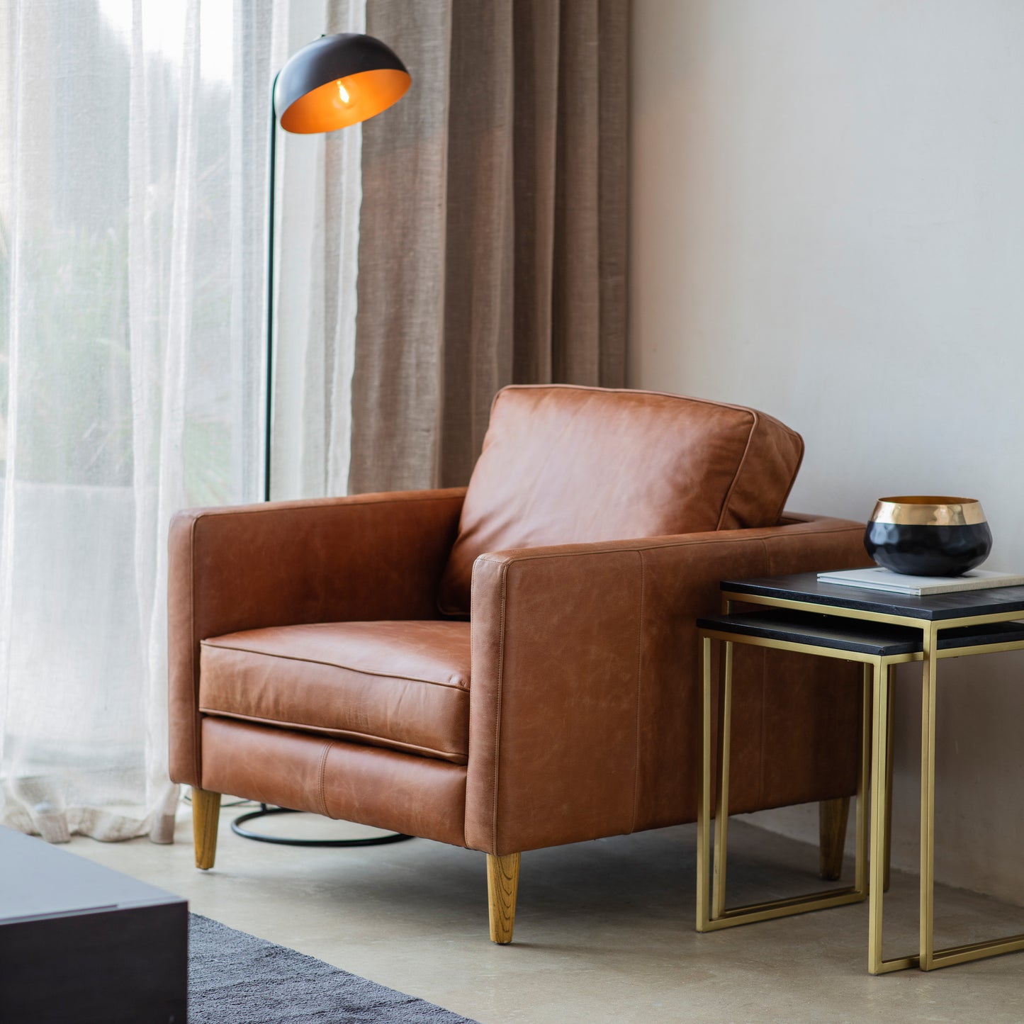 An Osborne Armchair in Vintage Brown Leather adds to the interior decor of a living room.