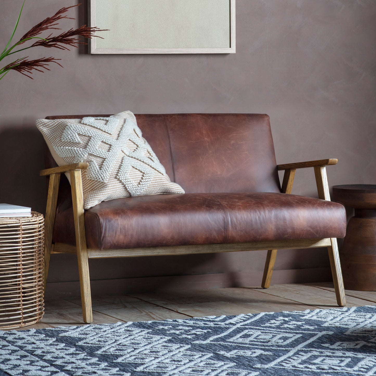 A vintage brown leather Neyland 2 Seater Sofa from Kikiathome.co.uk enhances interior decor in front of a brown wall.