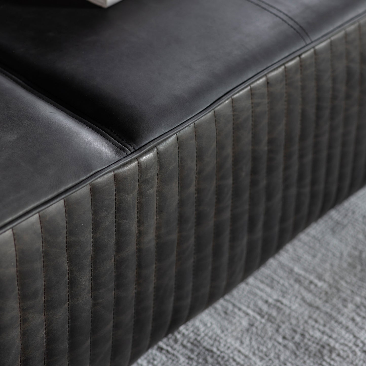 A close up of a Kikiathome.co.uk Cornwood Slab Black Leather 1200x1200x300mm couch for interior decor.