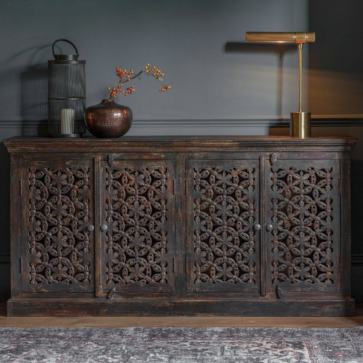 An ornate home furniture piece, the Chillington 4 Door Sideboard 1800x410x900mm by Kikiathome.co.uk, adds elegance to interior decor in a dark room