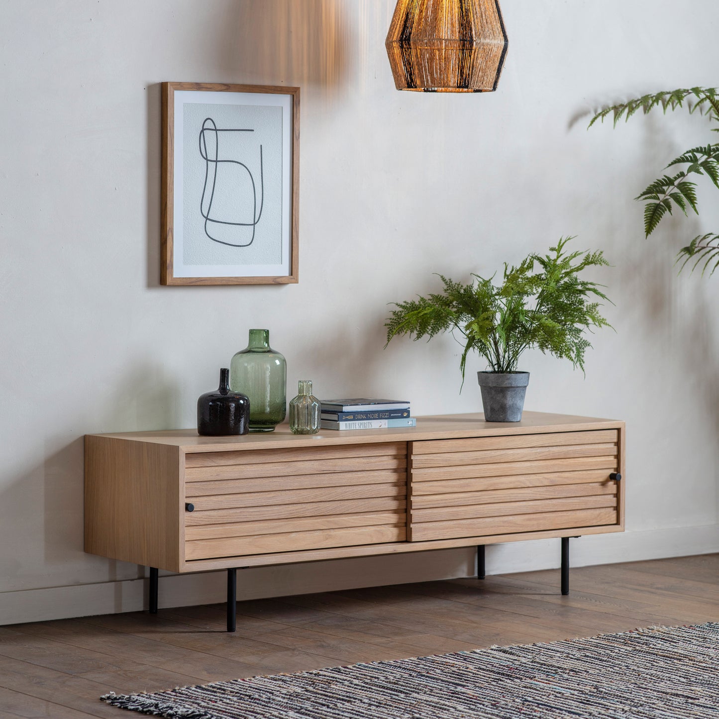 An interior decor featuring a Tortington Media Unit 1400x420x440mm as home furniture in a living room, alongside a potted plant.