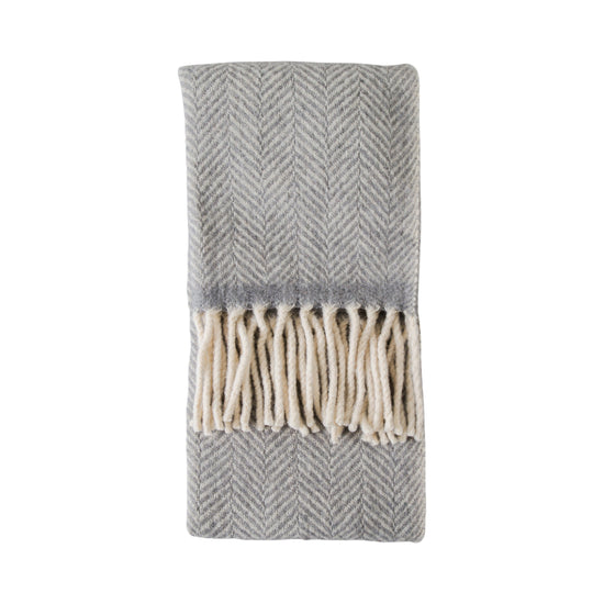 A Grey Wool Throw with fringes, perfect for interior decor.
