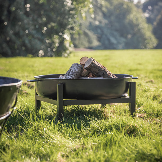 A grassy field transformed into a cozy outdoor space featuring a Parkham Firepit from Kikiathome.co.uk.