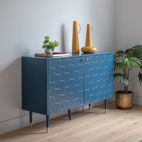 A blue 2 door cabinet by Kikiathome.co.uk, adding interior decor to a room with a potted plant.
