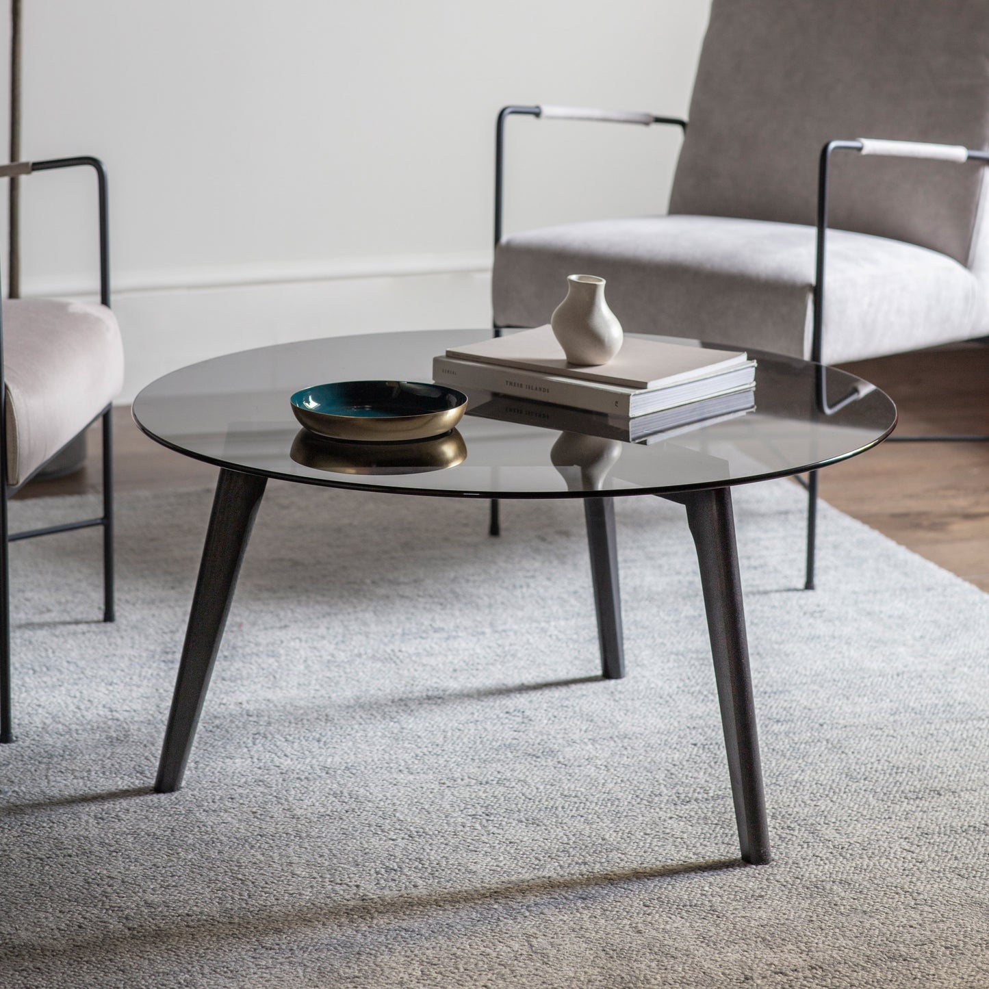 A black Ashprington Round Coffee Table in a living room, adding to the interior decor of the home.

