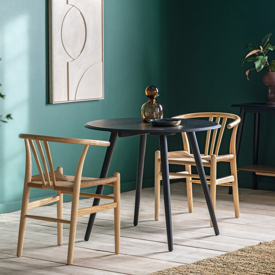 Two Maddox Round Dining Table 900x900x750mm chairs and a Maddox Round Dining Table 900x900x750mm table, creating a stylish interior decor setting with vibrant green walls