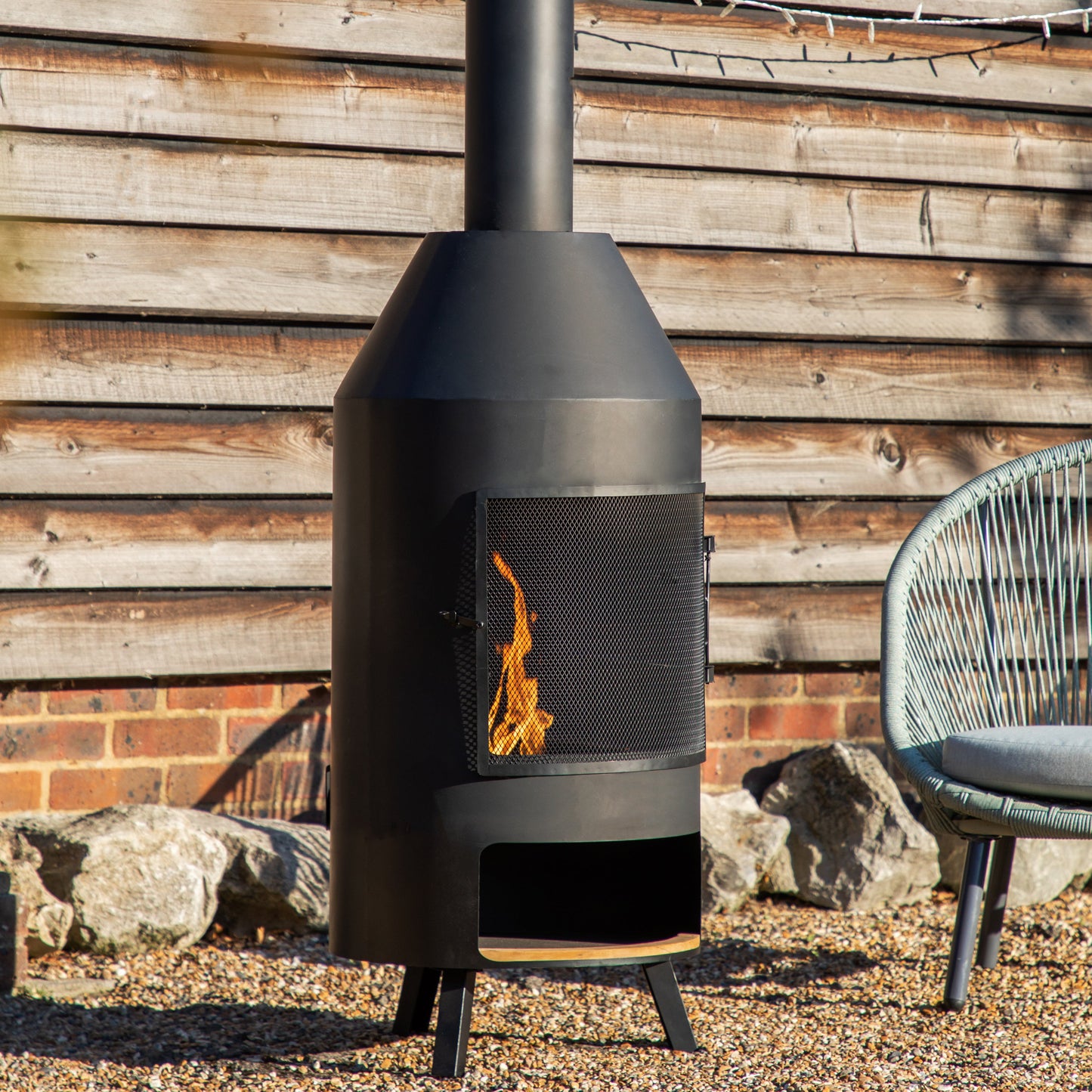 A Marldon Chiminea with Pizza Shelf 500x500x1835mm serving as home furniture and complementing interior decor, showcased in front of a brick wall.