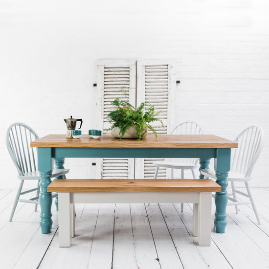 A rustic oak dining table with chairs and a bench, part of home furniture for interior decor, displayed in a white room.