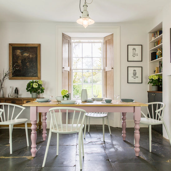A dining room with a pink table and chairs.