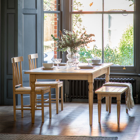 A Kikiathome.co.uk Buckland Extending Dining Table natural 1800/2300x950x750mm with two chairs in front of a window, perfect for home furniture and interior