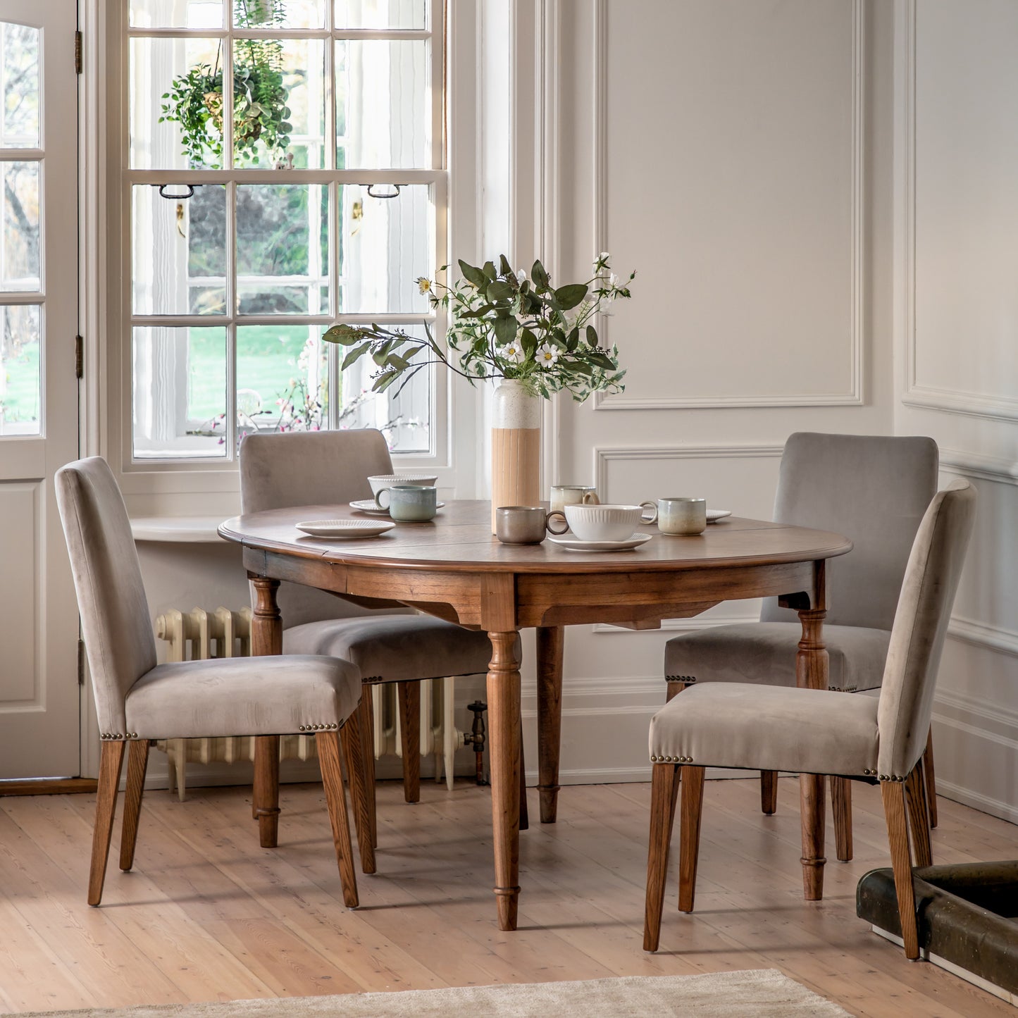 A dining room with a Kikiathome.co.uk Sweaton Extending Round Table 1200/1600x1200x750mm and chairs for elegant home furniture and interior decor.