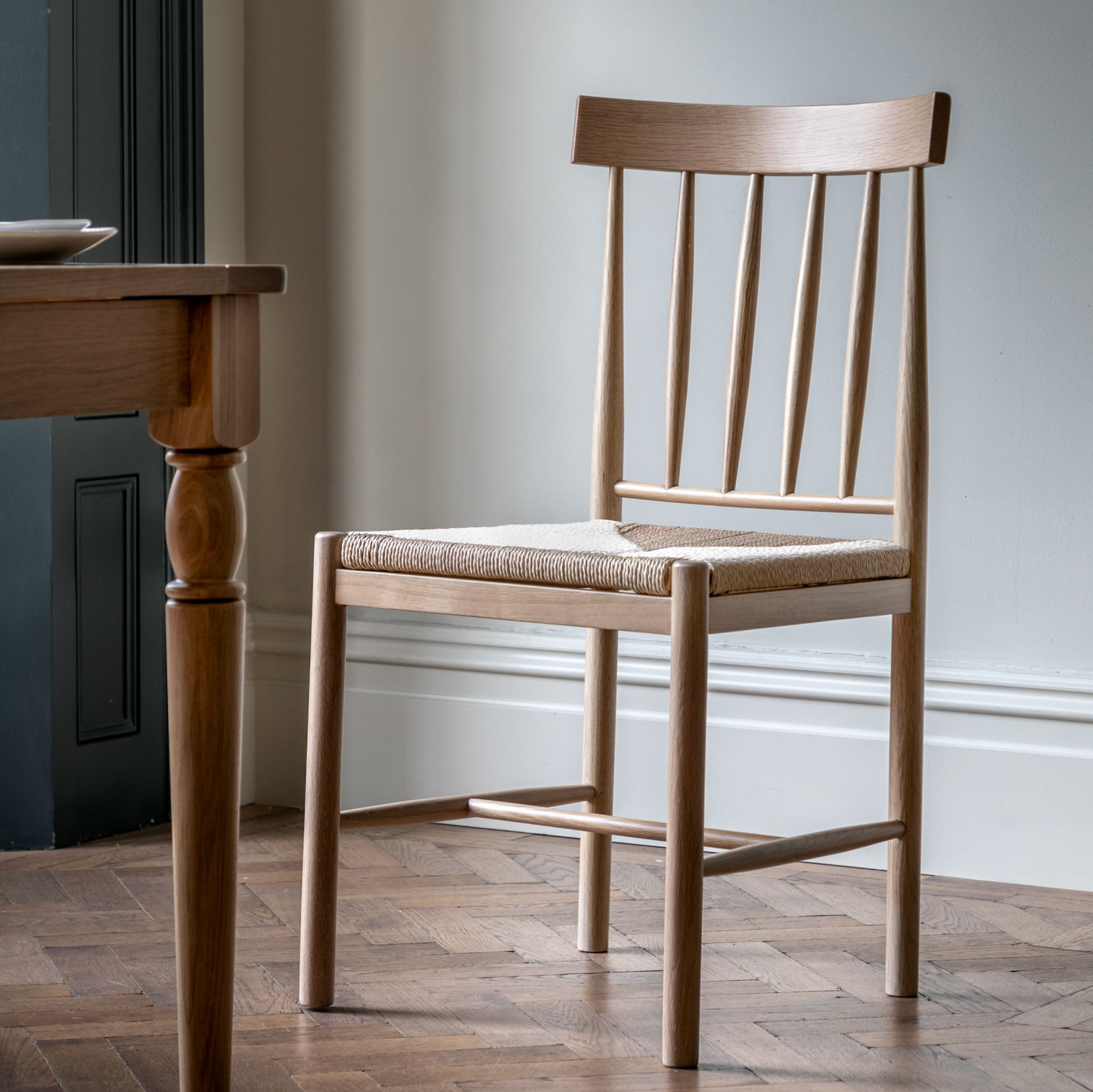 A pair of Buckland Dining Chairs in oak, from Kikiathome.co.uk, complements the interior decor of a room furnished with a wooden table.
