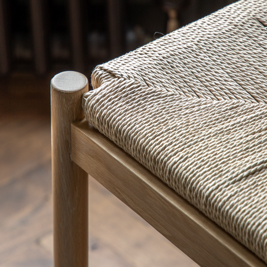 A close up of a Kikiathome.co.uk Buckland Oak Stool with a woven seat, perfect for interior decor.