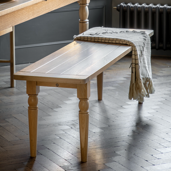 A Buckland Dining Bench in Oak from Kikiathome.co.uk adds to the interior decor of a room with a table and chairs.