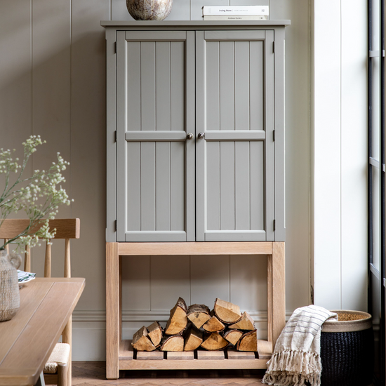 Load image into Gallery viewer, A Buckland 2 Door Storage Cupboard in Prairie (w)900x(d)450x(h)1700mm with logs on top of it, perfect for interior decor.

