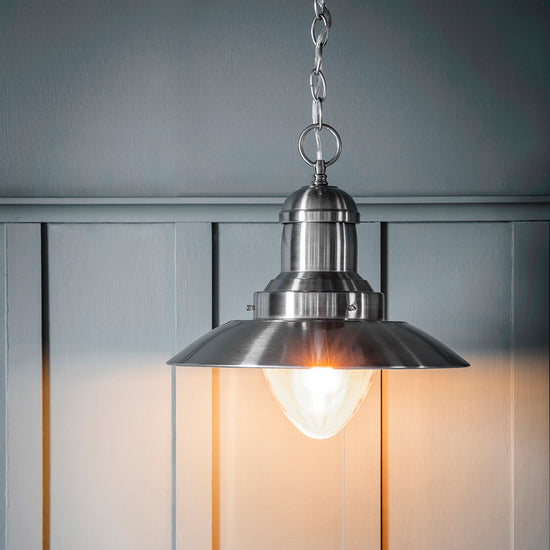 A Mendip Pendant Light hanging from a wooden wall, perfect for interior decor.