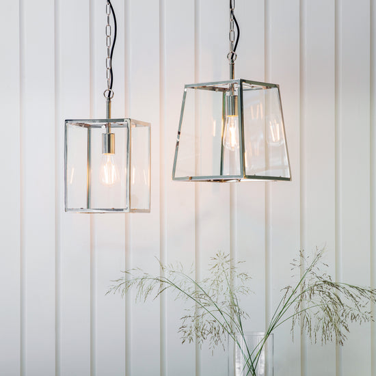 Two Hurst Pendant Light Nickel hanging from a wooden wall for interior decor.