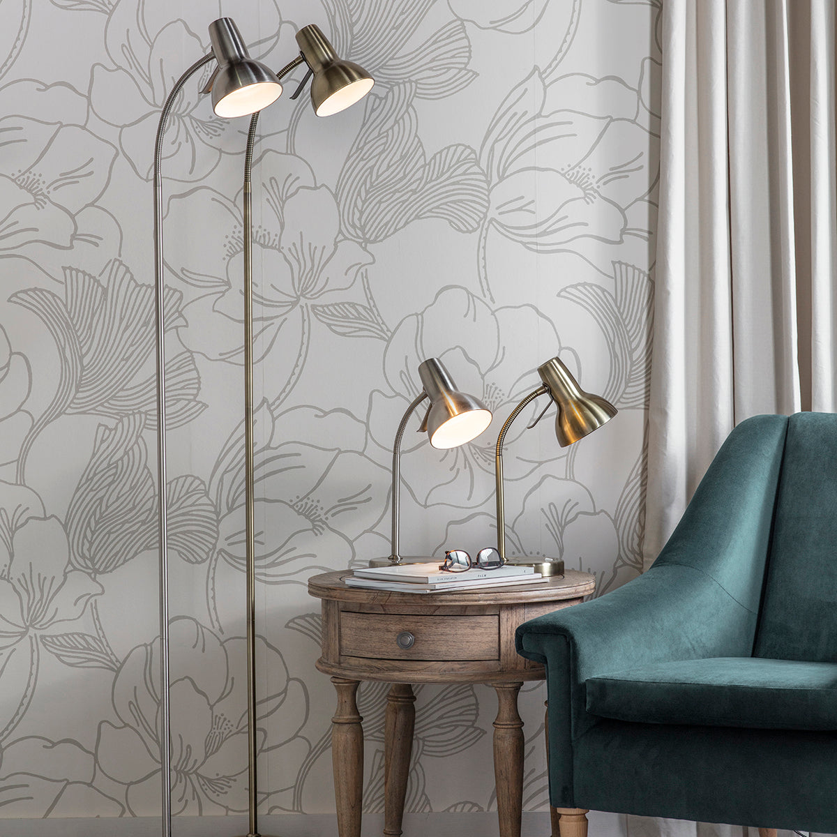 A Bickerton Floor Lamp Antique Brass by Kikiathome.co.uk enhances the interior decor with a chair in front of a floral wallpaper.