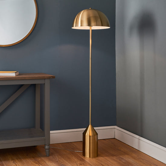 A Nova 1 Floor Light Antique Brass floor lamp, adding warmth to the blue-walled room.