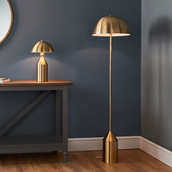 A Nova 1 Floor Light Antique Brass floor lamp next to a mirror, enhancing the interior decor of your home from Kikiathome.co.uk.