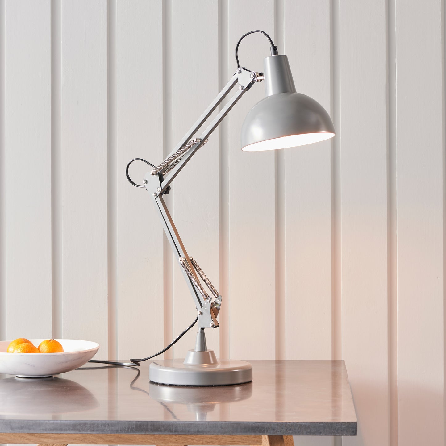 A Marshall 1 Table Light Slate Grey & White from Kikiathome.co.uk is on a table next to a bowl of oranges, showcasing interior decor.