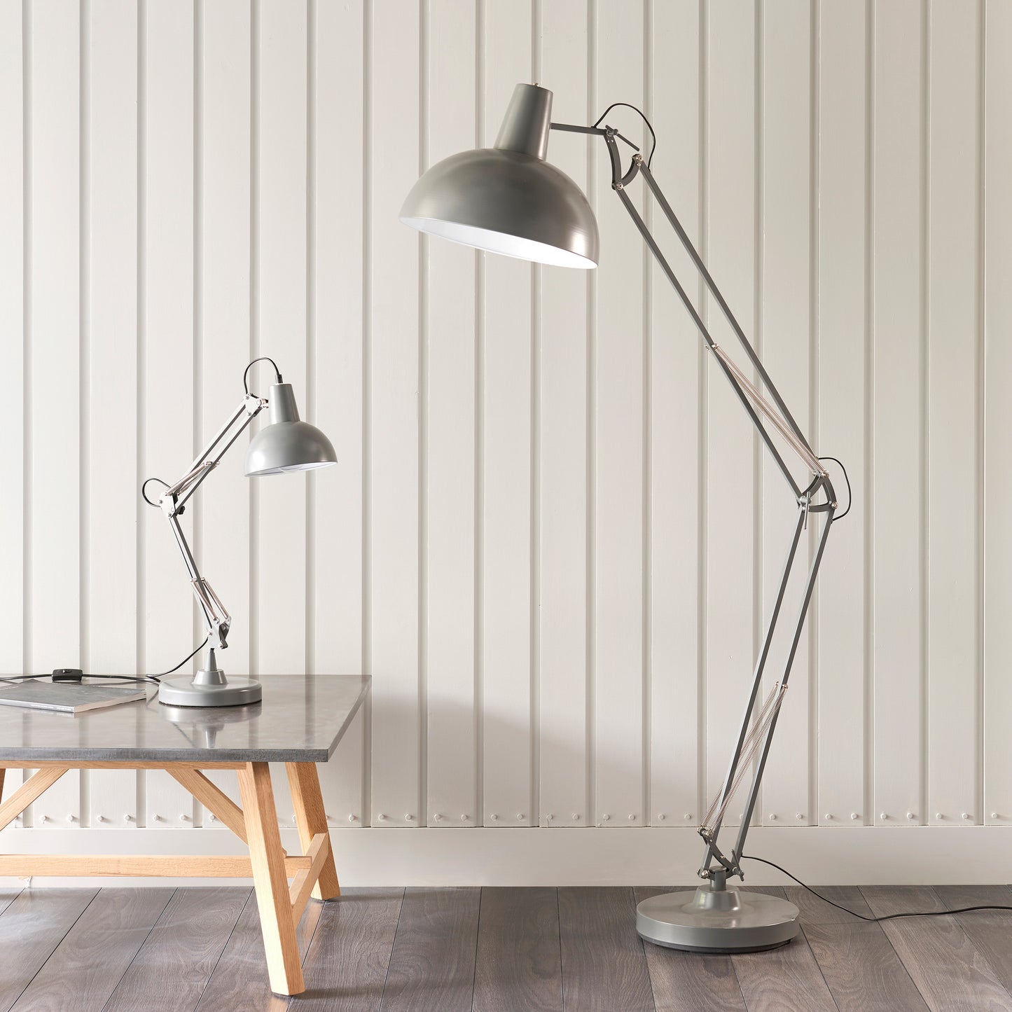 A stylish Marshall 1 Table Light Slate Grey & White floor lamp illuminates a wooden table, enhancing the interior decor of a room.