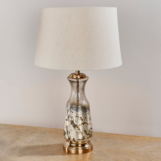 A Samuel 1 Table Light with a beige shade on a wooden table for home furniture and interior decor from Kikiathome.co.uk.
