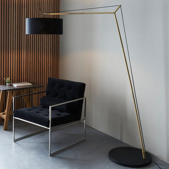 A black chair paired with a Buckland Floor Lamp Antique Brass for stylish home interior decor.
