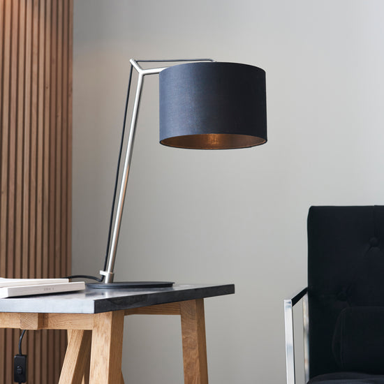 A Buckland Table Lamp Antique Nickel with a black shade and a black chair for interior decor.