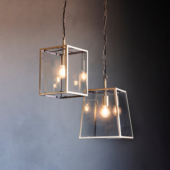 Two antique brass pendant lights hanging from a grey wall, adding style and warmth to your interior decor.