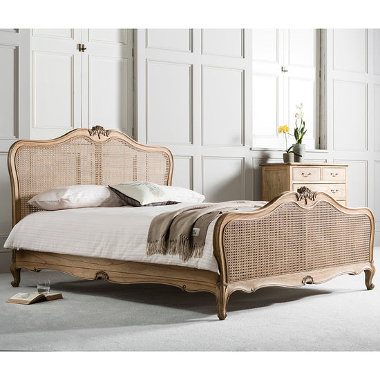 A weathered Holne 5' Cane Bed with a carved headboard and footboard, perfect for home furniture and interior decor.